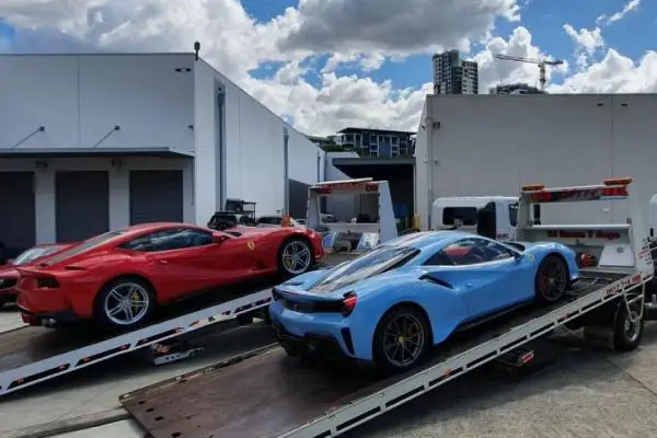 two supercars on tow trucks