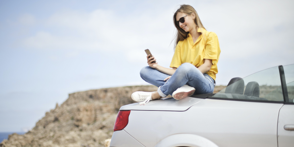 Woman sitting on car waiting for a tow truck